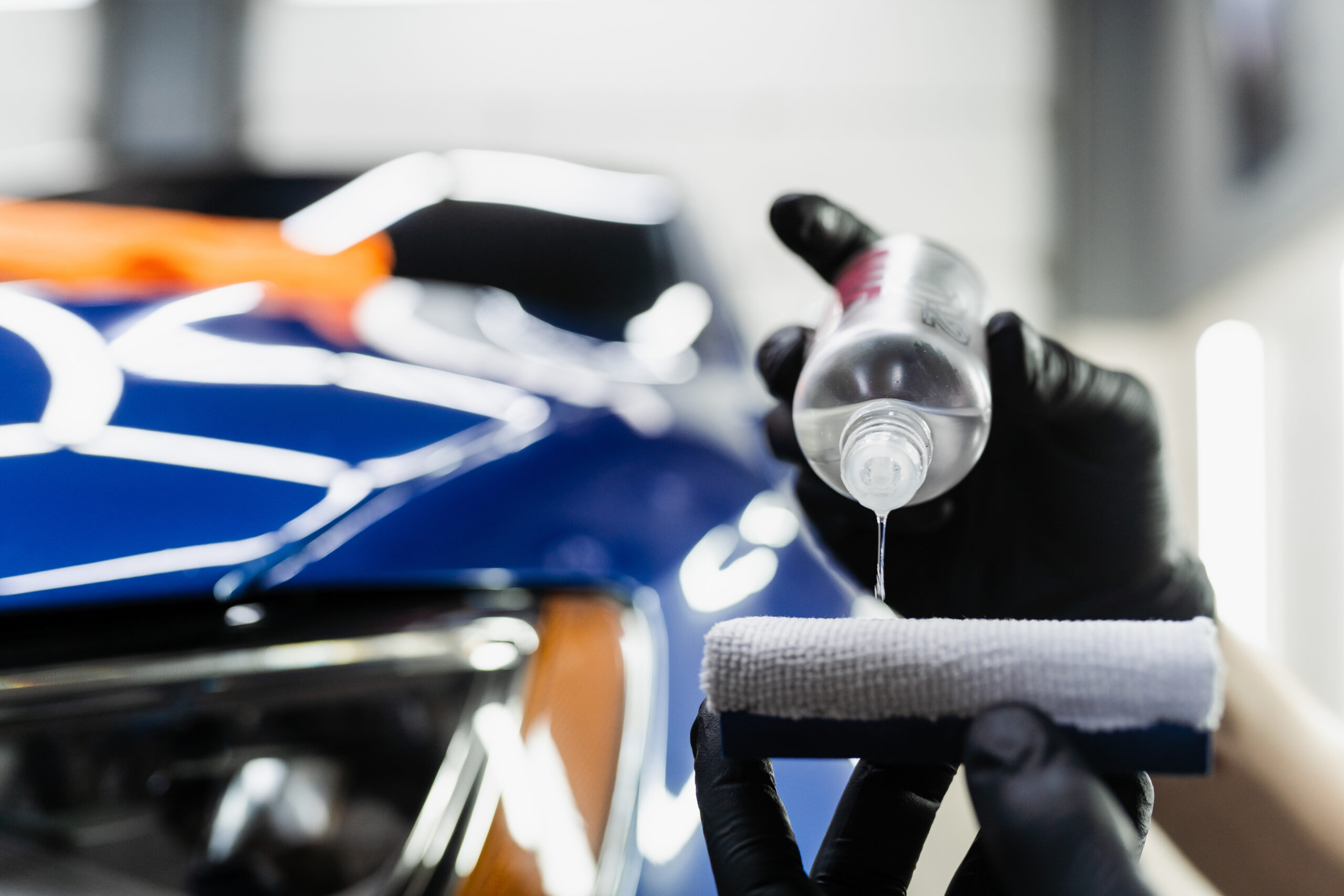 Technician applying ceramic coating to car with protective gloves