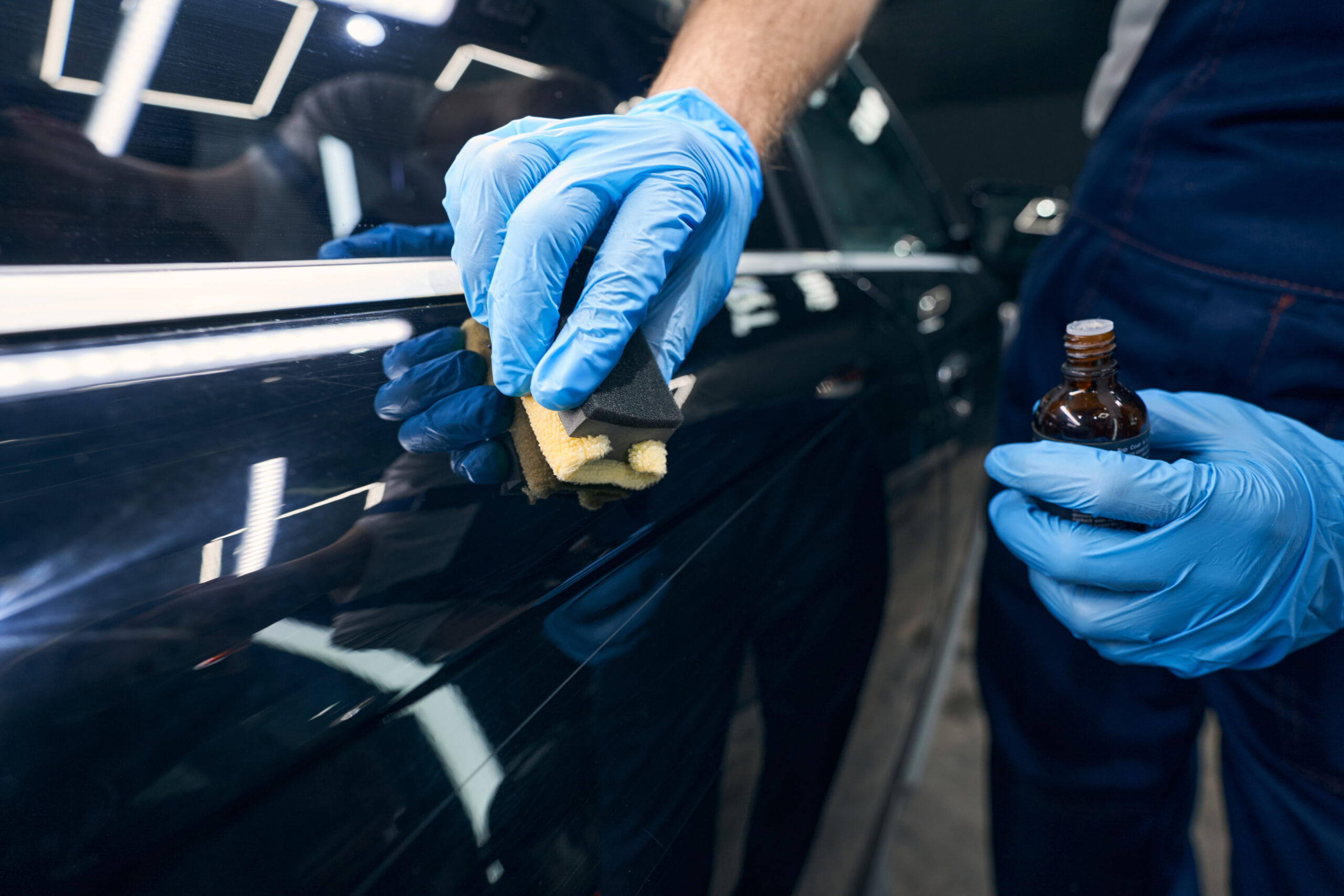Professional ceramic coating application on dark car paint surface