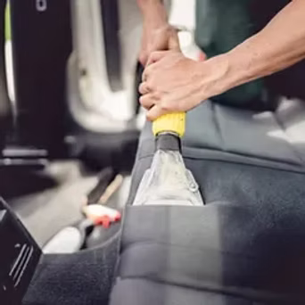 Professional steam cleaning and shampooing car seat upholstery with handheld extractor