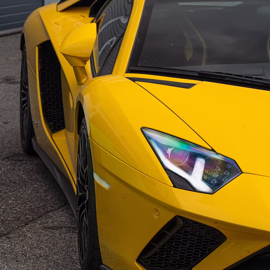 Bright yellow Lamborghini with open scissor door and detailed headlight