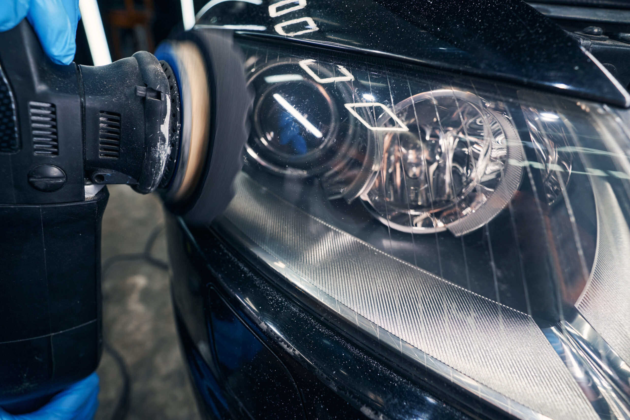 Professional headlight restoration on black car during detailing service