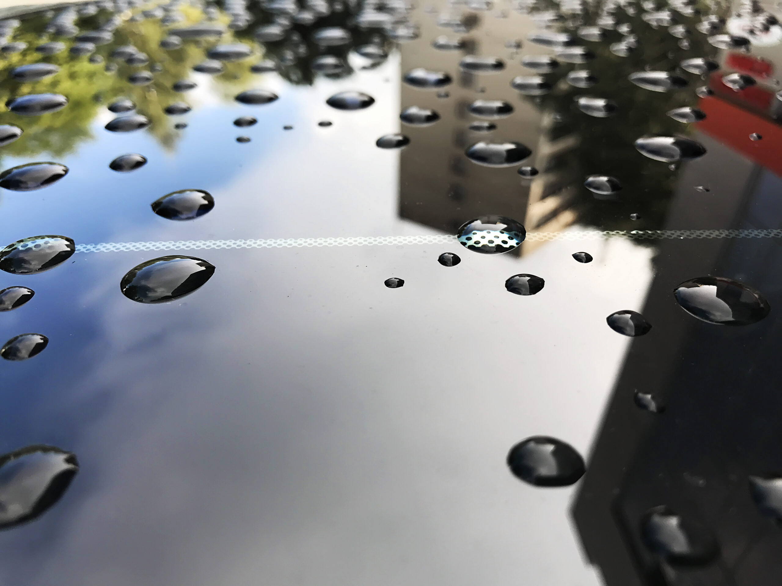 Water beads on hydrophobic car coating surface demonstrating water repellency