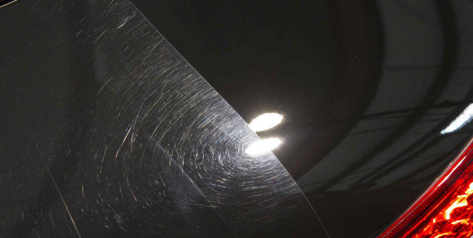 Swirl marks and scratches visible on dark car paint surface