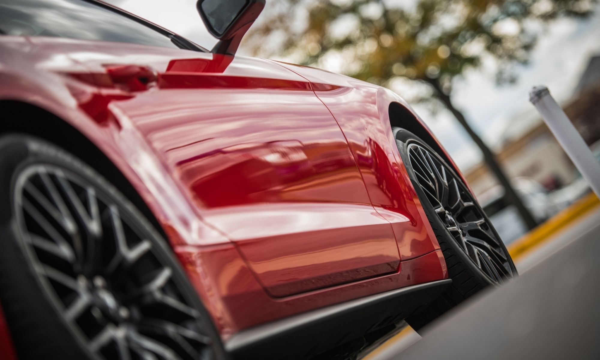 Red car with glossy mirror finish and dark alloy wheels parked outdoors