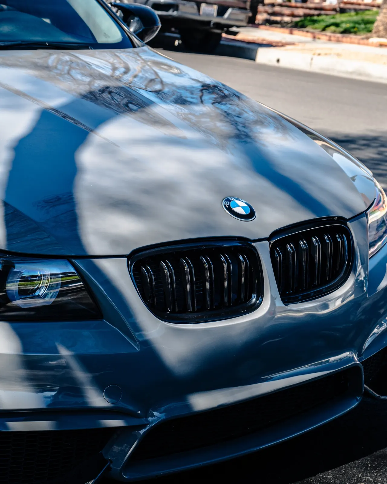 Professional paint correction service highlighting the restored glossy finish on a blue BMW.